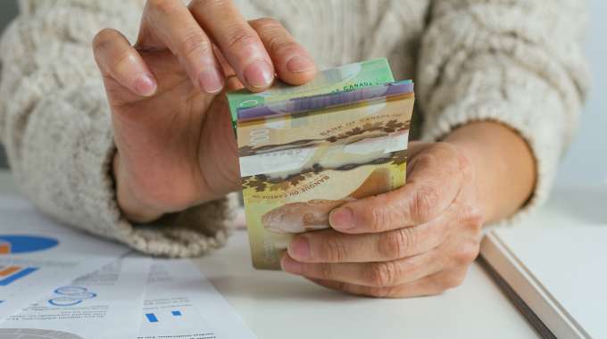 Person counting canadian money that they've saved through good saving habits