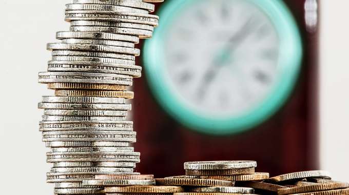 Coins next to clock-- Time is money, especially when it comes to saving and compound interest.