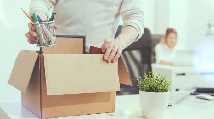 Person fills a box with personal belongings after losing their job