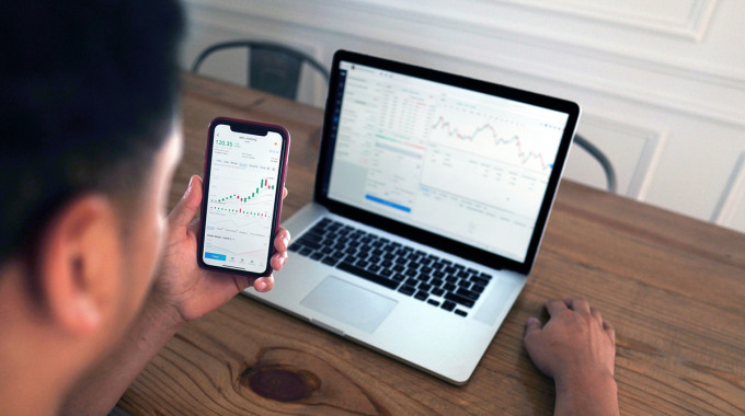 Man researches mutual funds and index funds on his laptop and smartphone